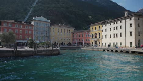 Panning-shot-of-III-November-Square-in-Riva-Del-Garda,-tourists-stroll