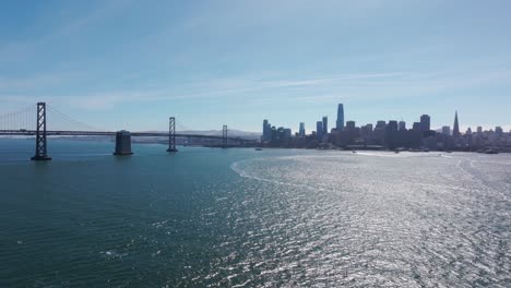 Disparo-De-Un-Dron-Volando-Hacia-El-Centro-De-San-Francisco-Con-El-Puente-Oakland