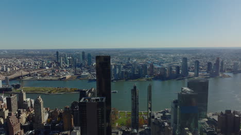 Aerial-panoramic-view-of-high-rise-building-on-East-River-waterfront-and-Queens-district-on-opposite-bank.-Clear-sky-on-sunny-day.-Manhattan,-New-York-City,-USA