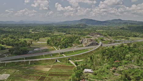 algama len viharaya sri lanka aerial v3 flyover fields by central expressway towards hillside buddhist cave rock temple amid lush jungle and mountain landscape - shot with mavic 3 cine - april 2023