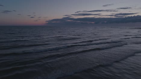 Tranquila-Playa-De-Owen-Sound-Al-Atardecer,-Suaves-Olas-Bajo-Un-Cielo-Degradado,-Serena-Escena-Natural