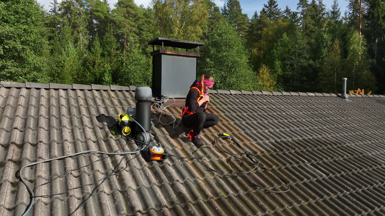 Aerial view of a woman wearing a harness for private house roof cleaning