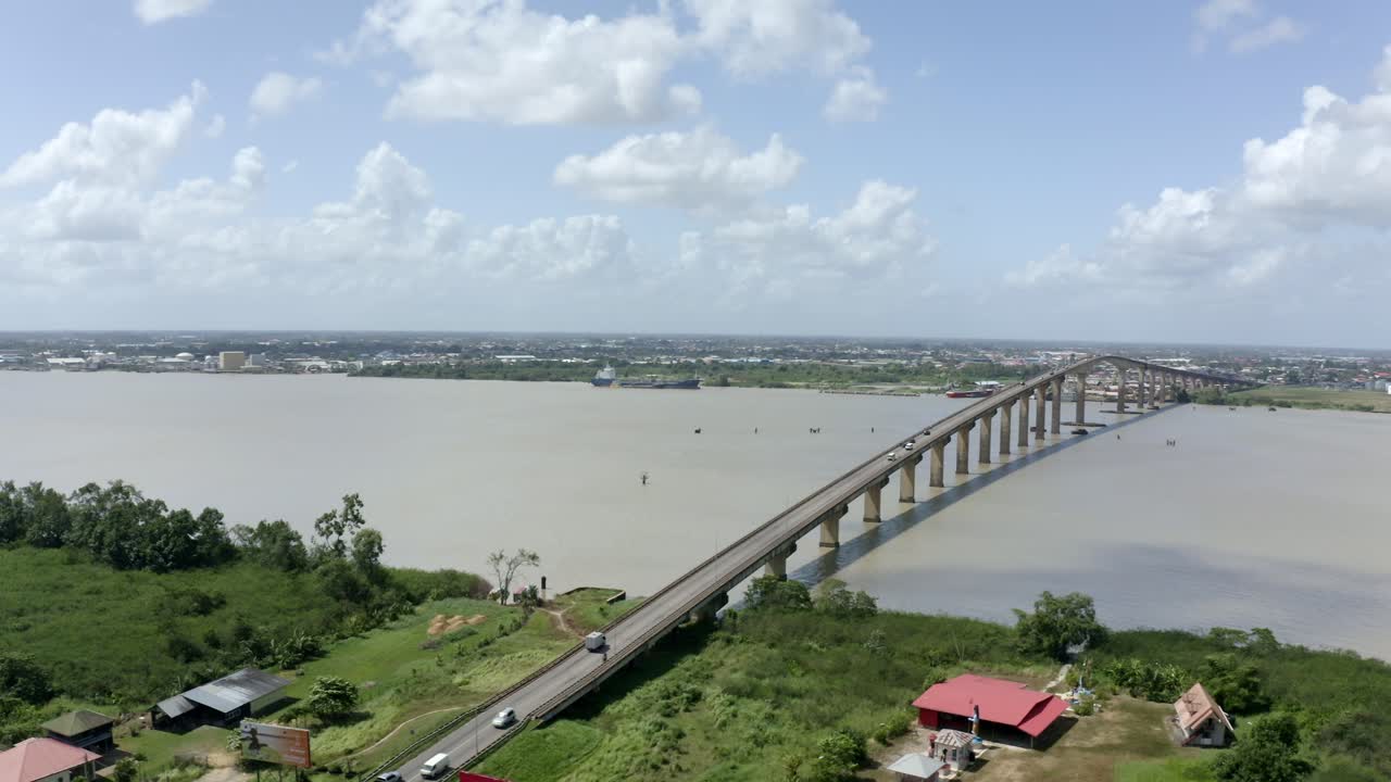 fotografía aérea de ángulo ancho del puente jules wijdenbosch entre paramaribo y meerzorg en suriname, américa del sur, con el tráfico mientras los drones orbitan alrededor del puente