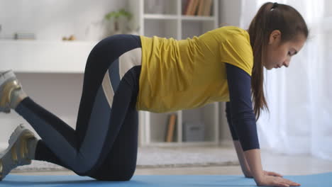 young slender woman is doing sporty exercise for legs training alone at home standing on floor in living room aerobics and gymnastics