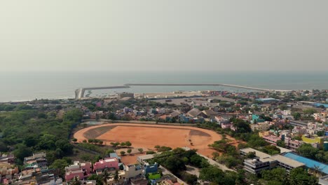 drone view of coastal city with a sport field in between and seascape at background.
