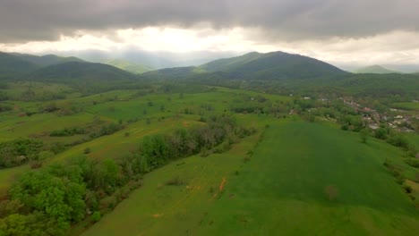 Wide-shot-soaring-towards-stormy-mountain-clouds-and-interesting-light-penetrating-and-illuminating-the-landscape