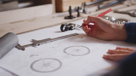 close up of female engineer in workshop making notes on plan for handmade bicycle