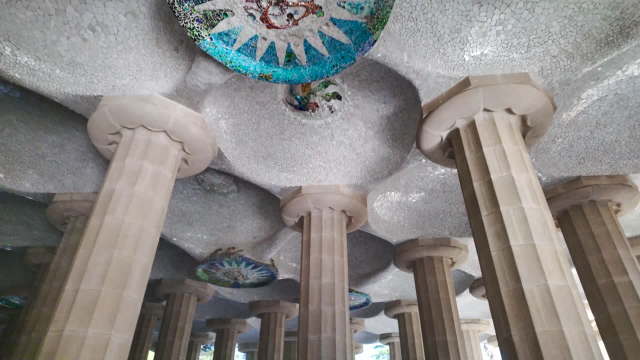 Close up view of the Hypostyle Room in Park Güell, featuring intricate columns and mosaic ceiling art, upward interior angle