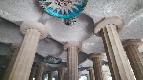 close up view of the hypostyle room in park güell, featuring intricate columns and mosaic ceiling art, upward interior angle