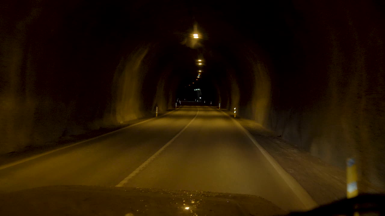 Driving car through dark yellow light Hvalfjörður Tunnel in slow motion with 4-wheel-drive in Island