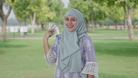 happy muslim woman money as fan in park