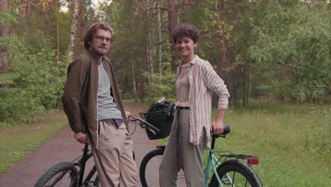 young affectionate couple with their son looking at camera with their bicycles in rural environment 1