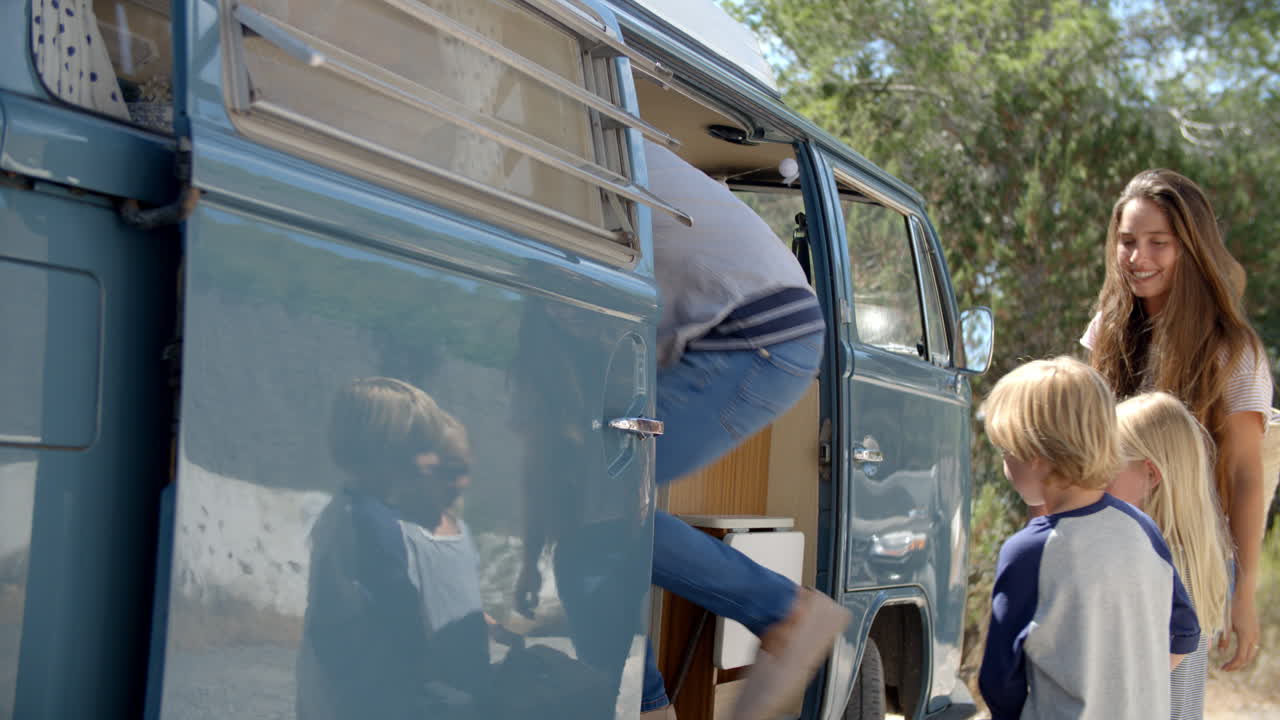 Family packing up their camper van for a road trip vacation