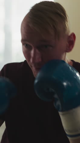 el deportista golpea una bolsa colgante en el gimnasio. el luchador profesional en guantes de boxeo entrena con una bolsa de golpeo en el club deportivo en cámara lenta. el atleta hace ejercicio.