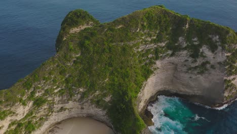 Acantilado-Empinado-De-Piedra-Caliza-Cubierto-De-Vegetación-Verde-Rodeado-De-Agua-De-Mar-Azul,-Playa-Kelingking,-Antena