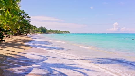 people swim at tropical sandy beach in summer in playa bonita, las terrenas, dominican republic