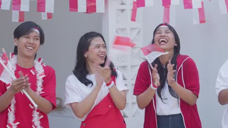 group of young man and woman clapping hands and giving high five to celebrating indonesian independence day, august 17