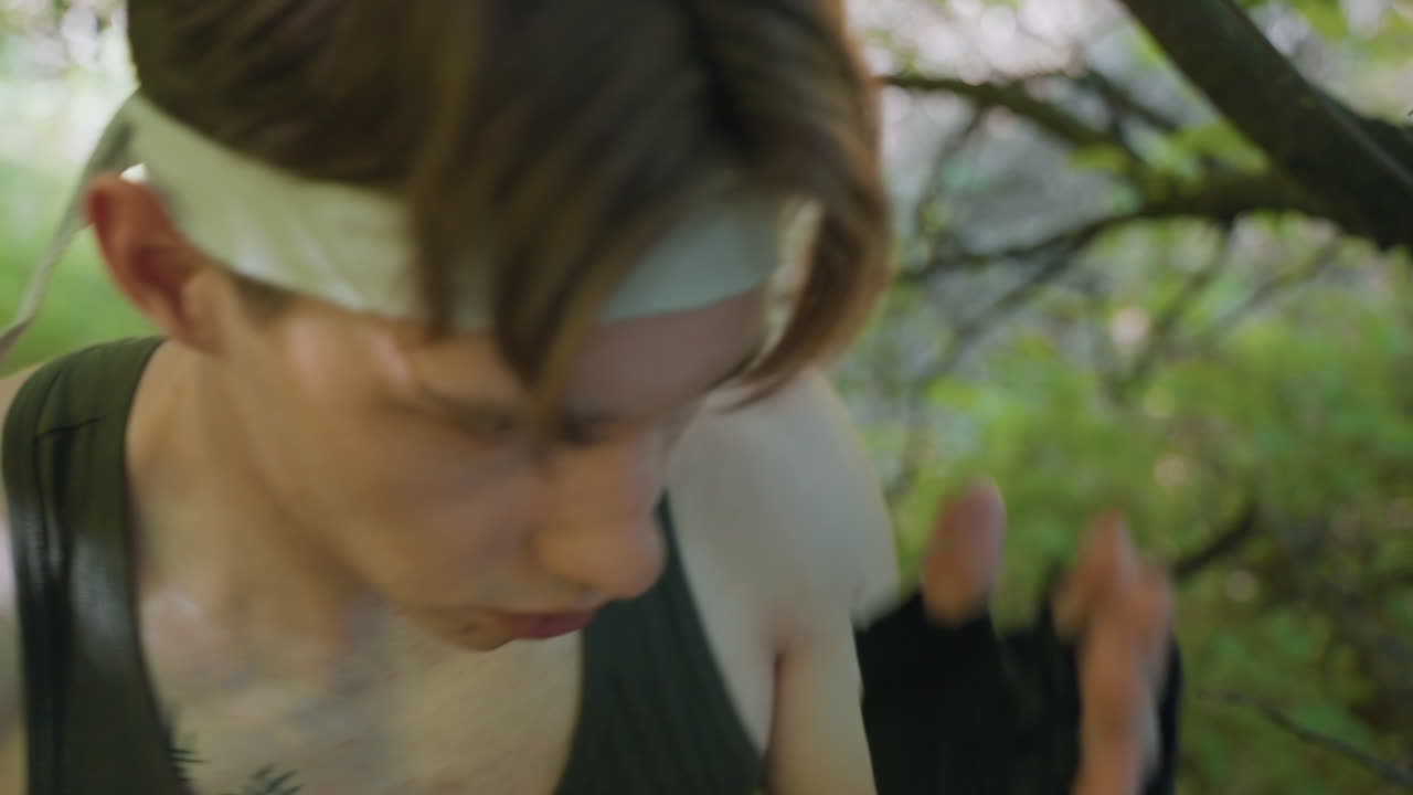 warrior wearing headband launching three rapid punches with gloved hand, tattooed chest and freckles on skin, intense focus and motion blur against forest backdrop conveying dynamic combat training