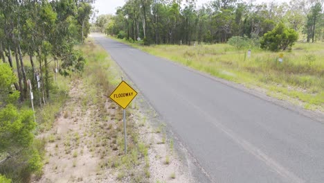 roadside floodway sign amidst forested landscape