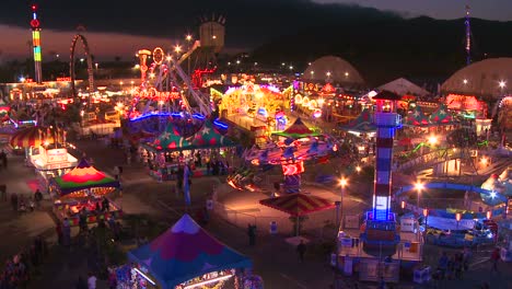 una vista de ángulo alto sobre un parque de diversiones bien iluminado con muchos juegos y atracciones 2