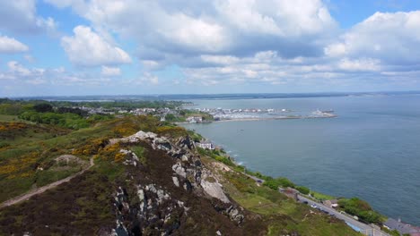 aerial reveal footage of howth town from behind rocky hills