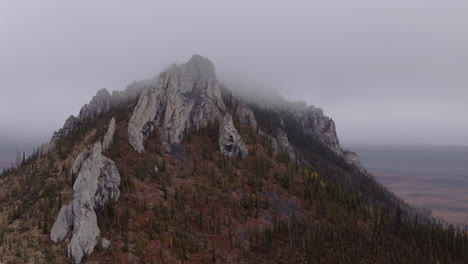 ogilvie mountains with rocky peak against overcast sky in yukon territory of northwestern canada. aerial shot
