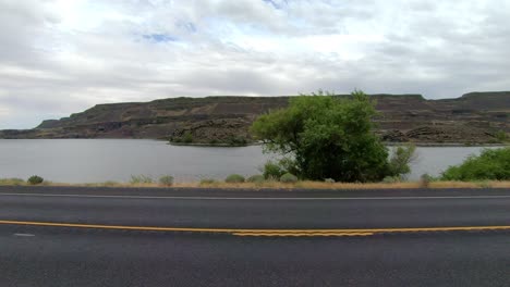 POV-of-the-passenger-of-a-parked-Class-A-RV,-point-of-view-of-Blue-Lake-and-traffic-on-Highway-17-in-Washington-State-on-a-cloudy,-windy-day