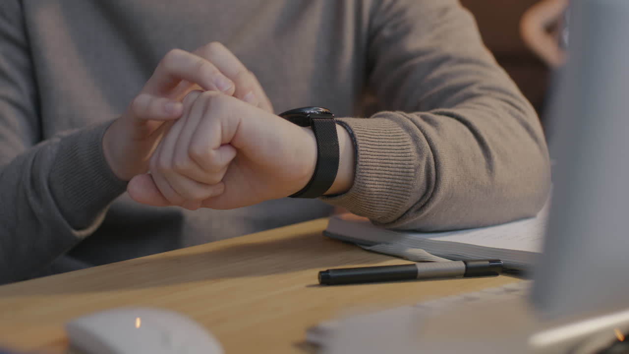 Person checking time on smartwatch at a desk
