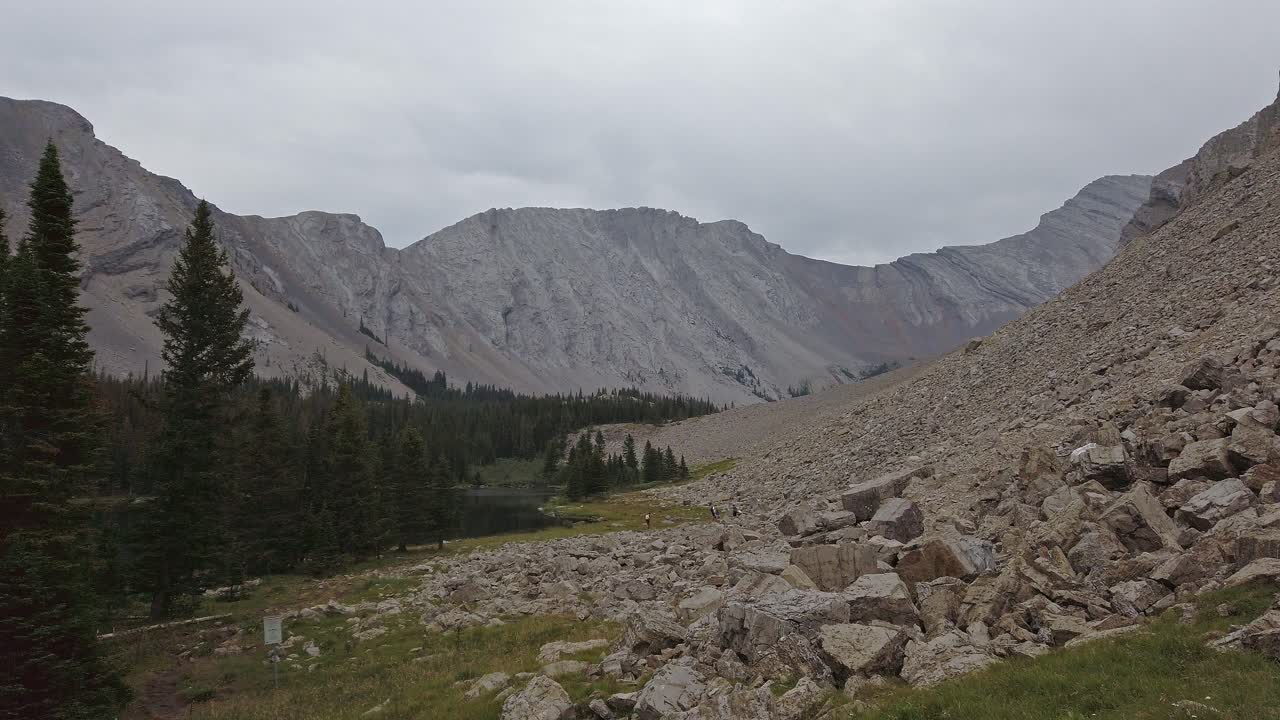 los excursionistas en la distancia dentro del valle de la montaña se acercaron a las rocas rocosas de kananaskis, alberta, canadá