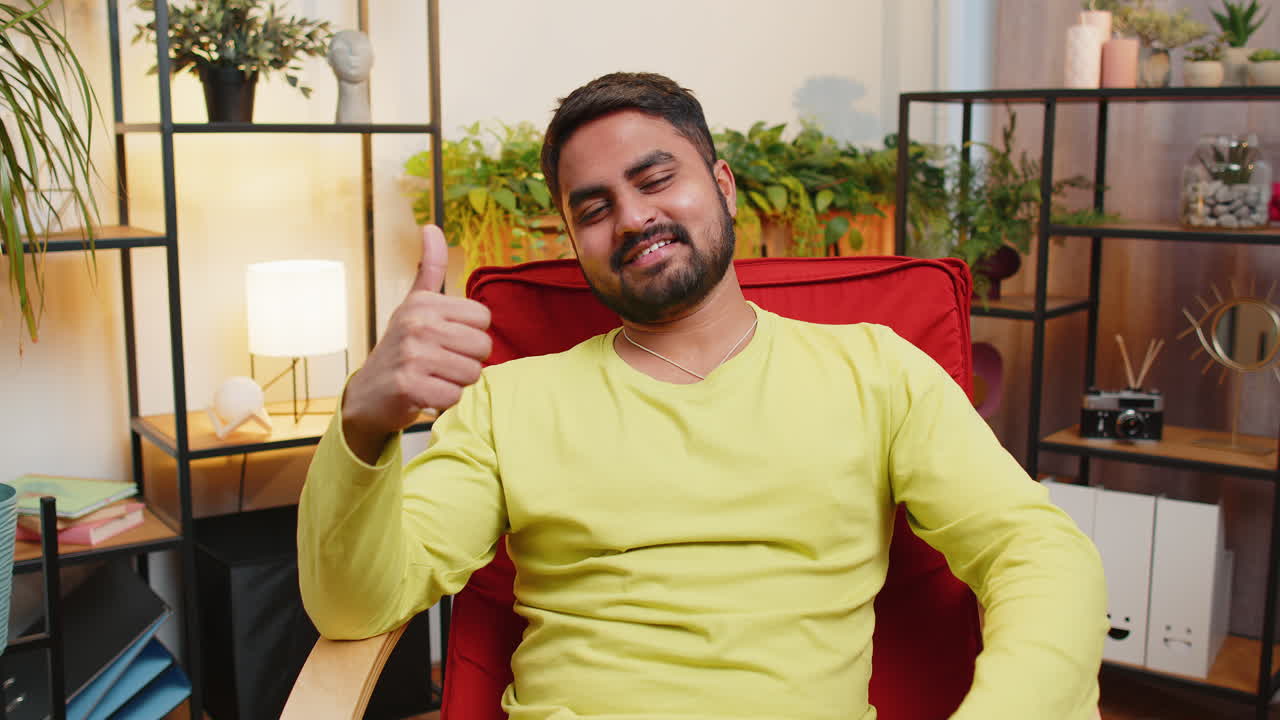 joven indio feliz mirando con aprobación a la cámara muestra los pulgares hacia arriba como un signo positivo buenas noticias