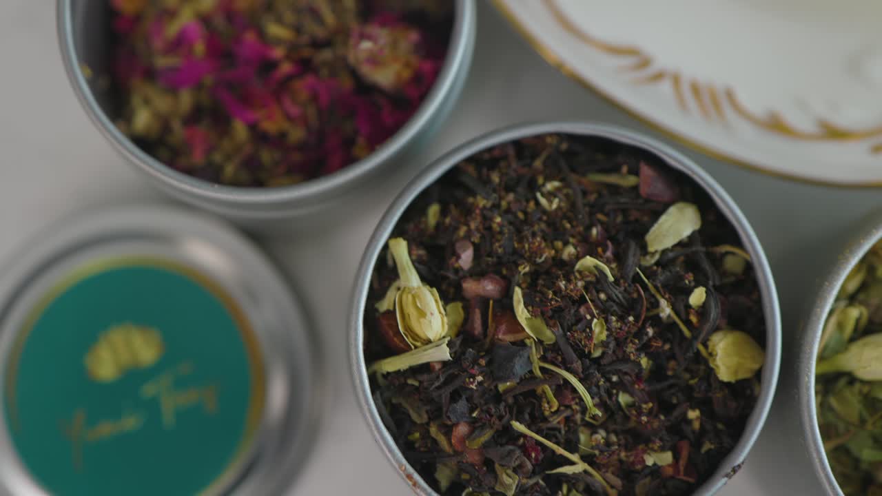 용기에 담긴 다양한 유기농 찻잎의 패닝 샷을 닫습니다.