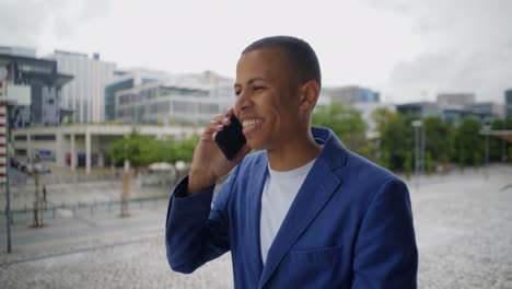 cheerful businessman wearing blue suit talking on smartphone.