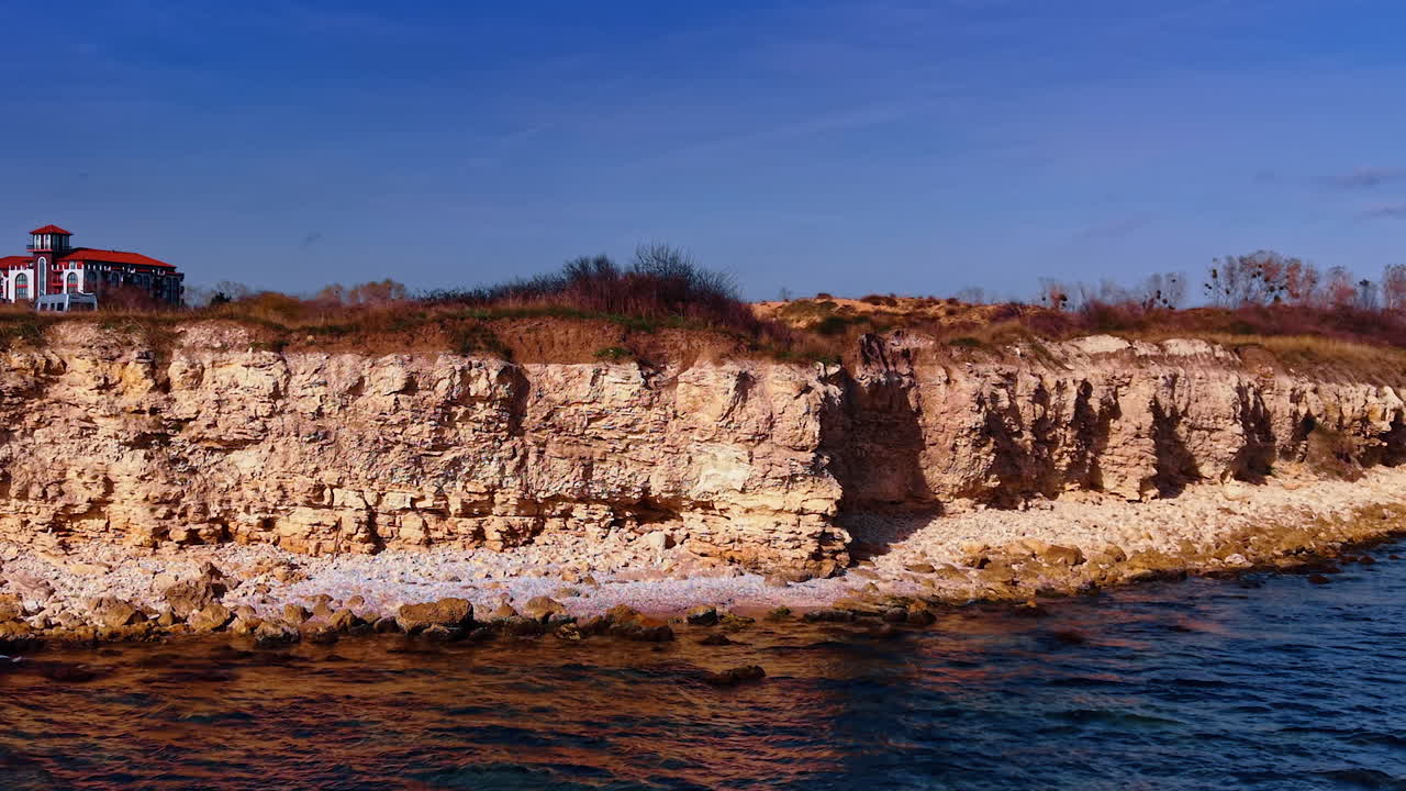 Filmato lungo la costa rocciosa di ripide scogliere. Vista sulla splendida casa con tetto rosso sullo sfondo