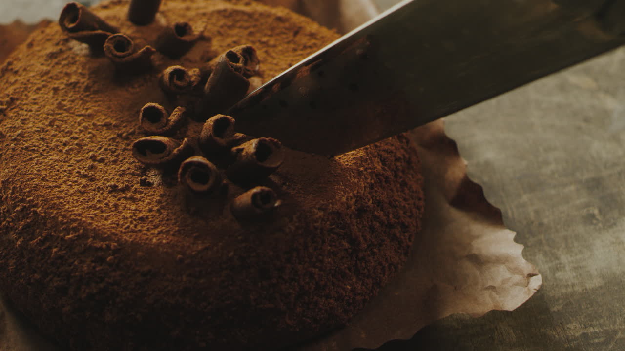 Closeup sharp knife cutting cake with chocolate shavings in slow motion.