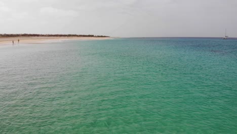 Vuelo-Bajo-Aéreo-Sobre-Las-Hermosas-Aguas-Azul-Turquesa-Del-Océano-Junto-A-Una-Playa-Idílica