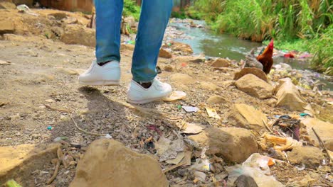 a man walking in an african slum in kenya called mathare slums towards a river that is heavily polluted by dumping of all the waste from houses nearby thus causing the river to be hazardous