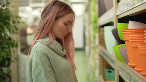 woman choosing colorful pot for home plants in flower shop