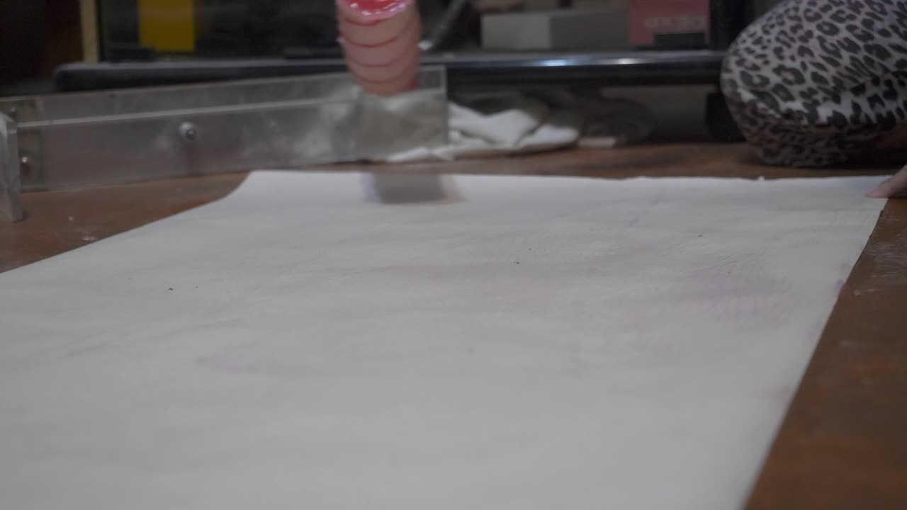 Wallpaper application in progress; adhesive is being evenly distributed with a roller. A close-up view showcases the home improvement task