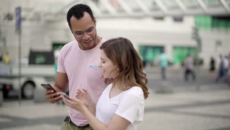 Side-view-of-two-young-people-walking-with-smartphones