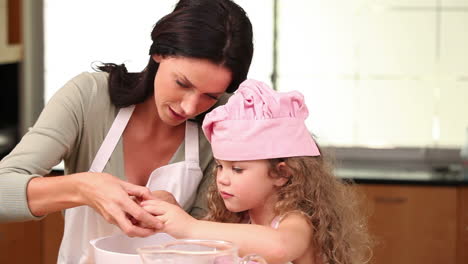 mother showing her daughter how to open an egg