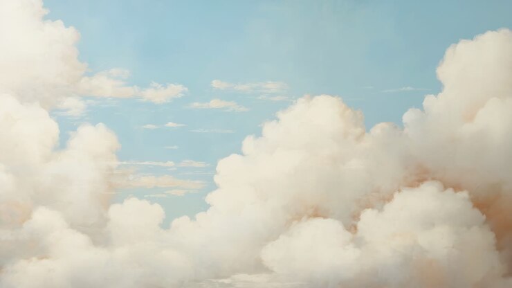 A serene, wide-angle video shot of fluffy white clouds against a clear blue sky, evoking a sense