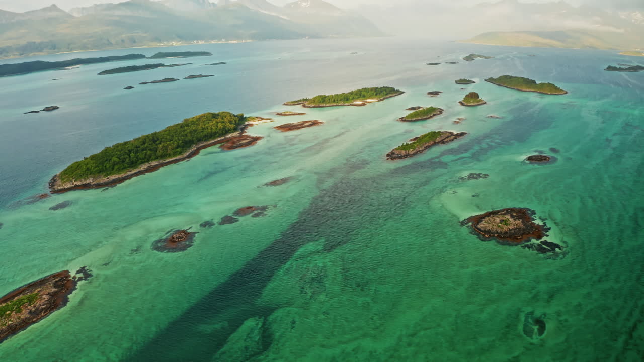 Aerial drone shot over the island of Senja in the Lofoten Ilsands, Norway. High view of the vibrant turquoise sea and the small islands. Breathtaking landscape, untouched natural wonder.