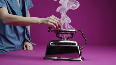 mujer manipulando el humo de un antiguo teléfono en forma de hierro