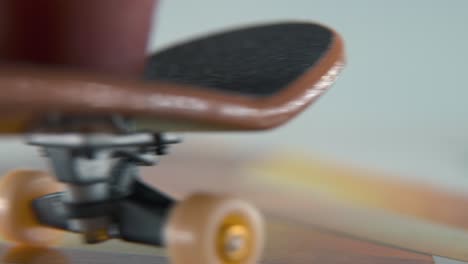 un macro de primer plano detallado de un mini skateboard, pequeñas ruedas blancas, montar fingerboard de derecha a izquierda, deslizamiento de dedos hacia atrás y hacia adelante, iluminación profesional, vídeo estático cinematográfico 4k