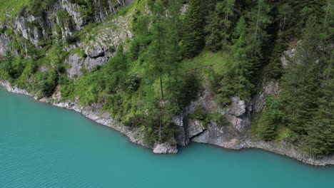 un cuerpo de agua tranquilo rodeado de exuberantes áreas boscosas dominadas por el lago tranquilo que tiene pequeñas ondas en su superficie y refleja los árboles circundantes en sus aguas tranquilas rocas esparcidas alrededor