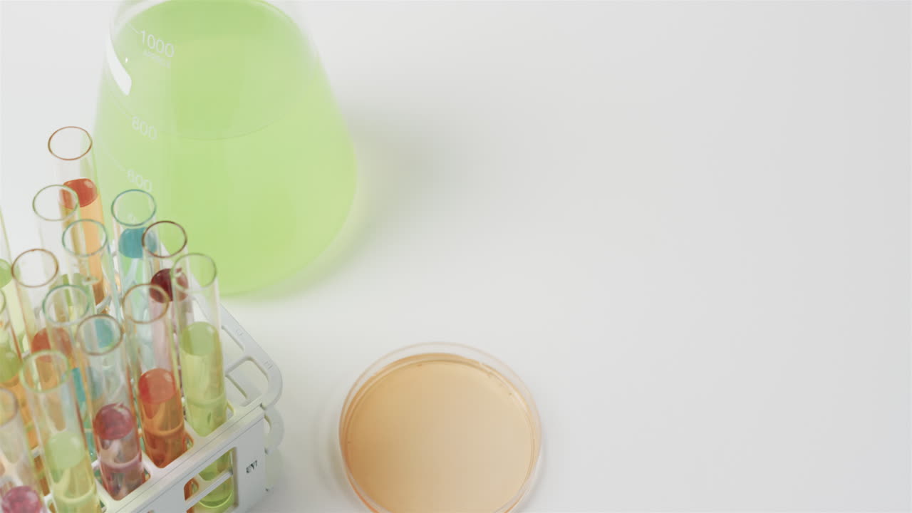 컬러 액체는 백색 배경에 시험 튜브가 서서히 움직이는 컵에 담겨 있습니다.