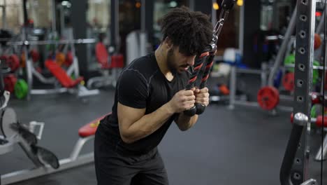 joven haciendo ejercicio en una estación múltiple en el gimnasio para los músculos del brazo