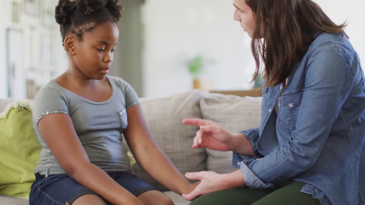 Caucasian woman arguing with her african american daughter in living room