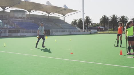 Hockeytrainer-Mit-Spielerinnen-Auf-Dem-Spielfeld