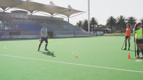 hockey coach with female players on the field